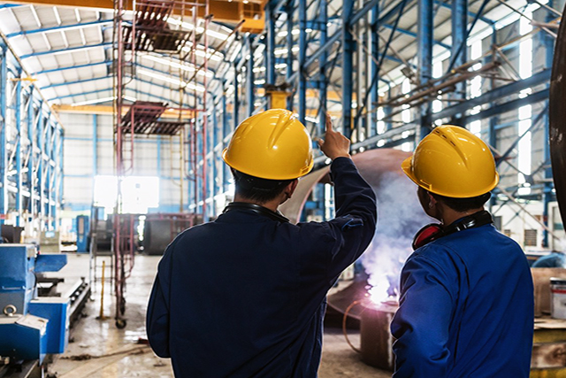 ¿Tu empresa es realmente segura? Guía técnica para instalar rutas de evacuación en Lima y Arequipa. 2 ingenieros instalando señales de seguridad ruta de evacuación reglamentarias en una planta de Lima